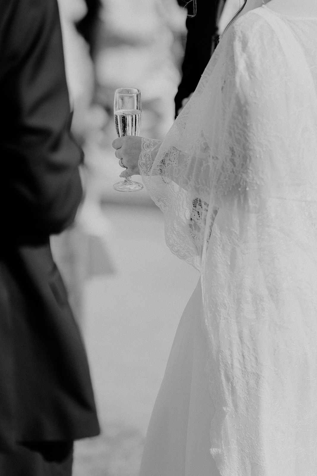 Bride holding prosecco in black and white close-up, intimate Peak District wedding moment.