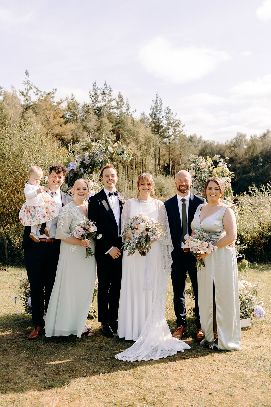 Couple with two guests in green, standing in golden hour light, relaxed countryside feel.