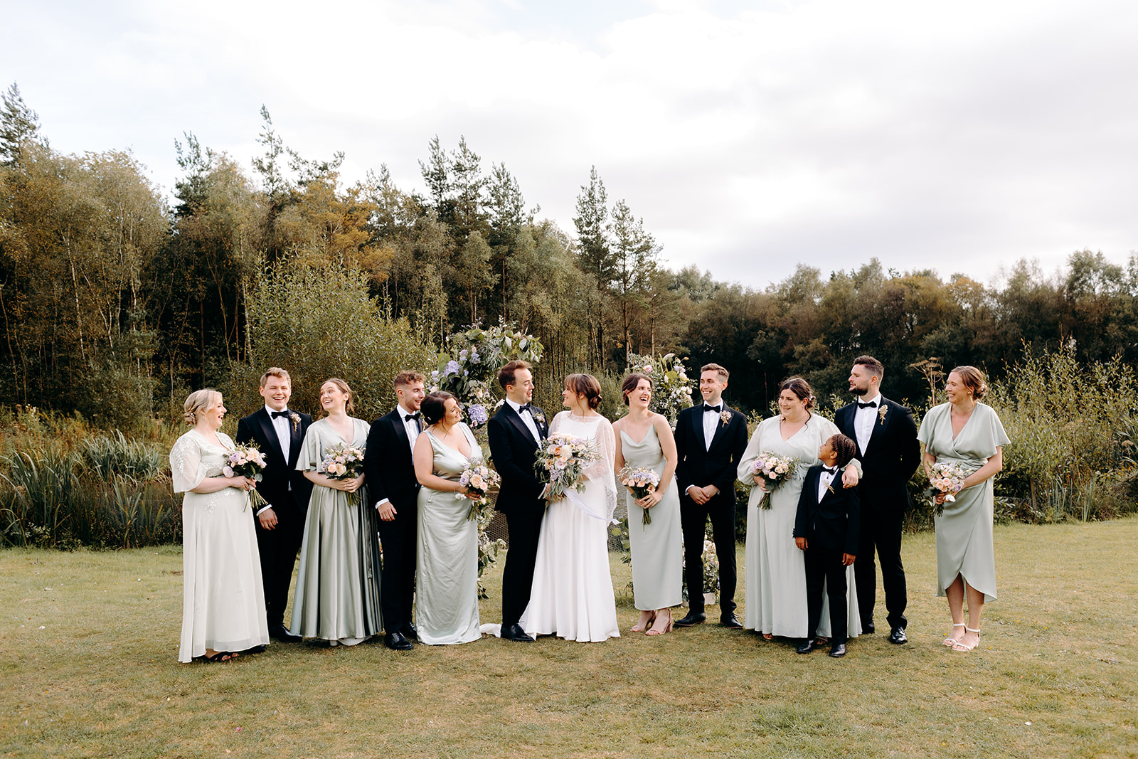 Full bridal party cheering together in golden sunlight, joyful and fun wedding photography in Derbyshire.