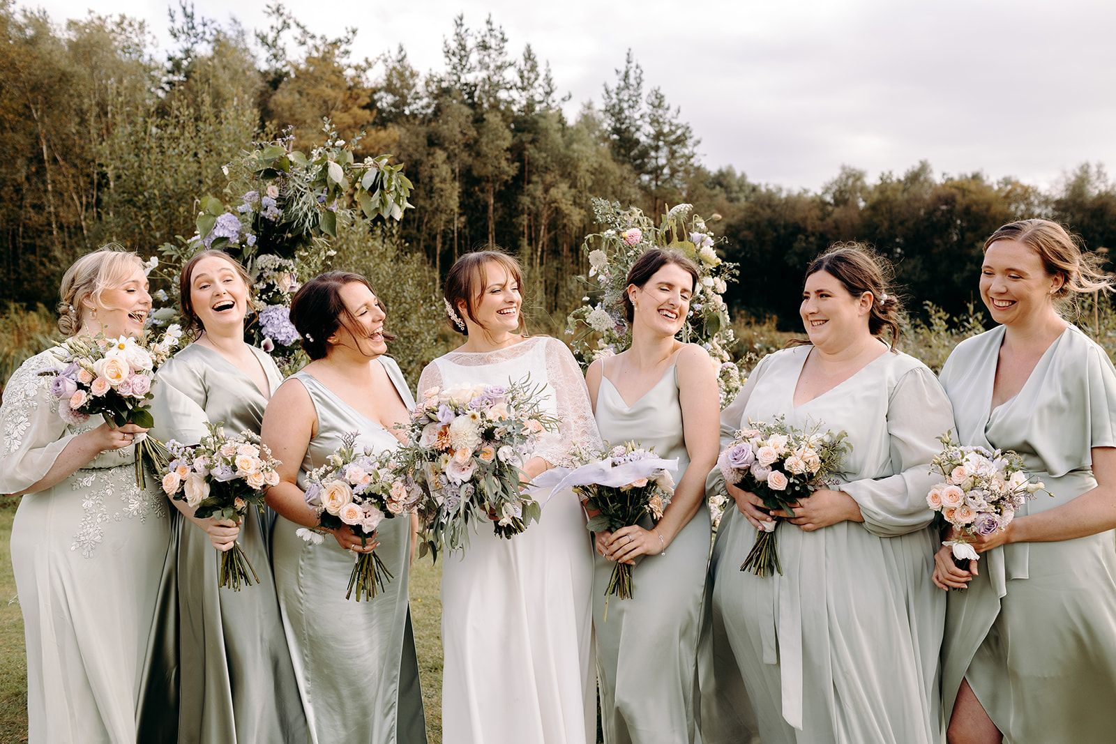 Bridesmaids cheering together in golden sunlight, joyful and fun wedding photography in Derbyshire.