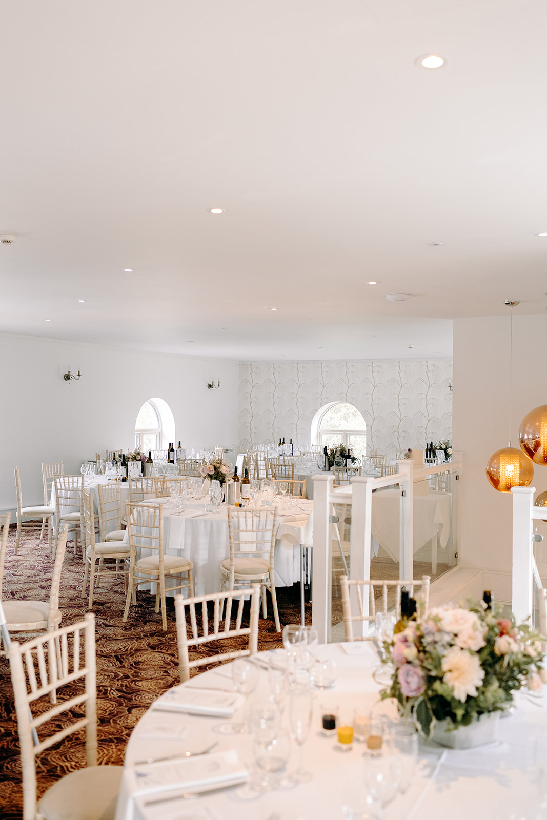 Bright, airy indoor reception setup with white chairs and elegant florals at Darwin Lakes.