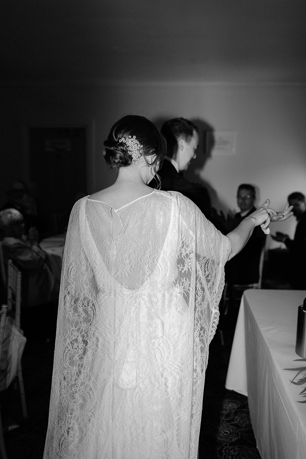 Black and white photo of bride walking into wedding breakfast room at Darwin Lakes.