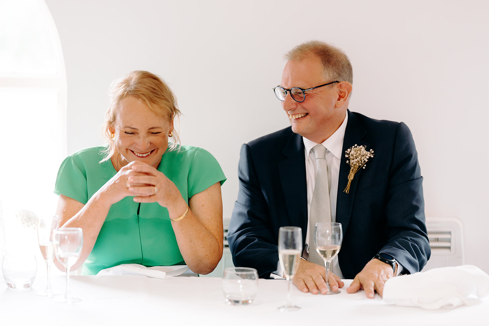 Natural photo of the mother and father of the bride laughing at the speeches at a Peak District wedding.