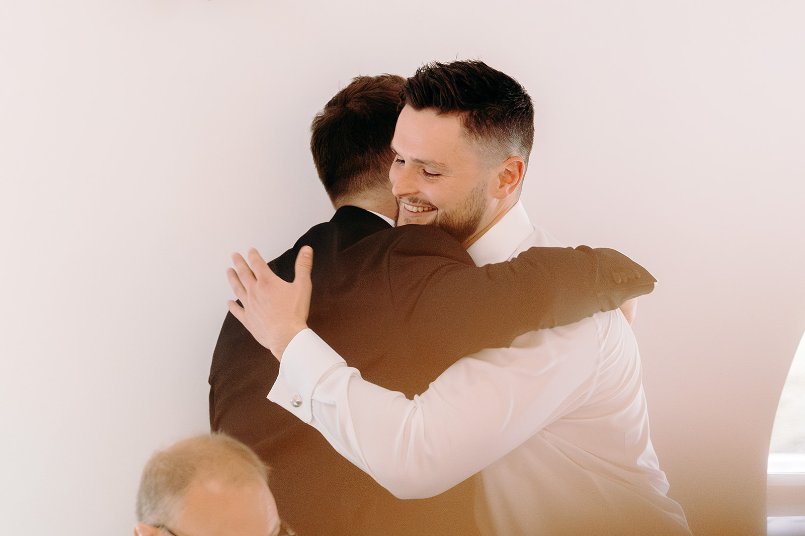 Natural wedding photography in the Peak District of groom hugging his best man following their speeches.