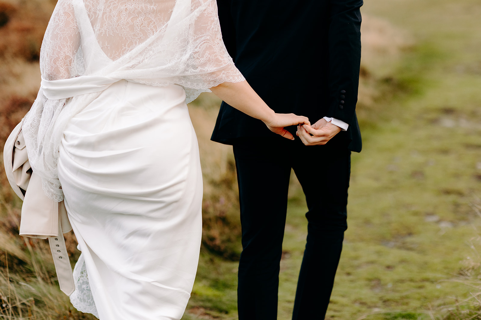 Bride and groom hand in hand, walking through the Peak District for their sunset wedding photos