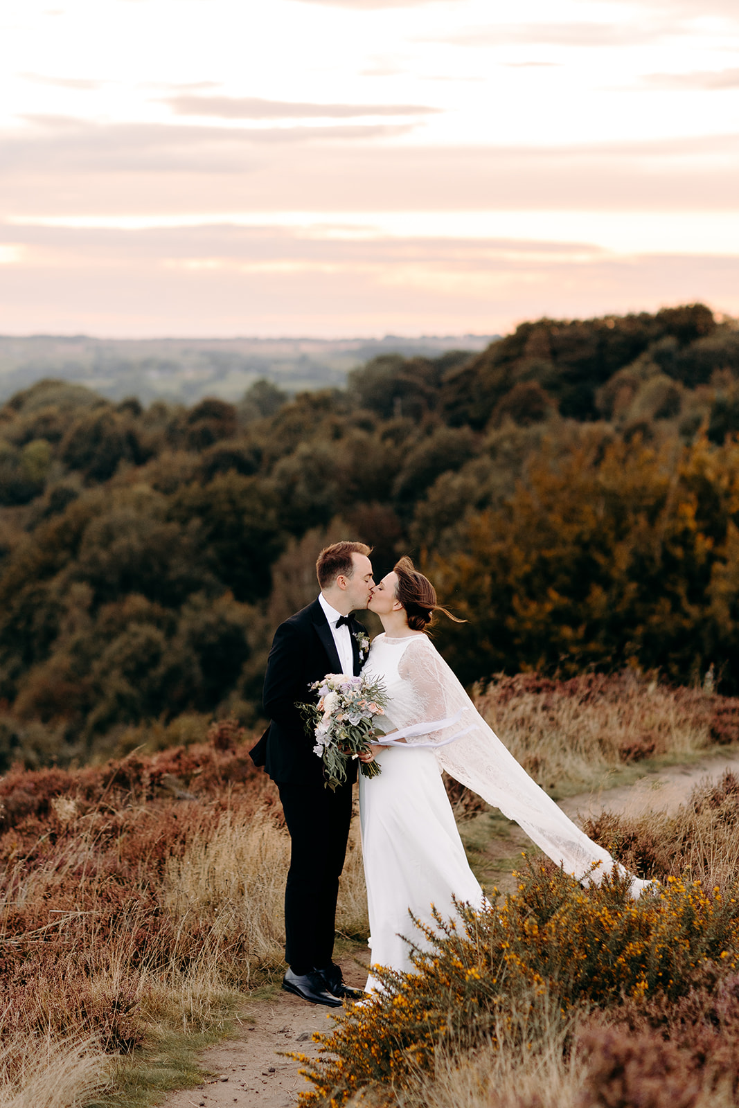 Groom twirls bride joyfully among the heather at their Derbyshire wedding in the Peak District.