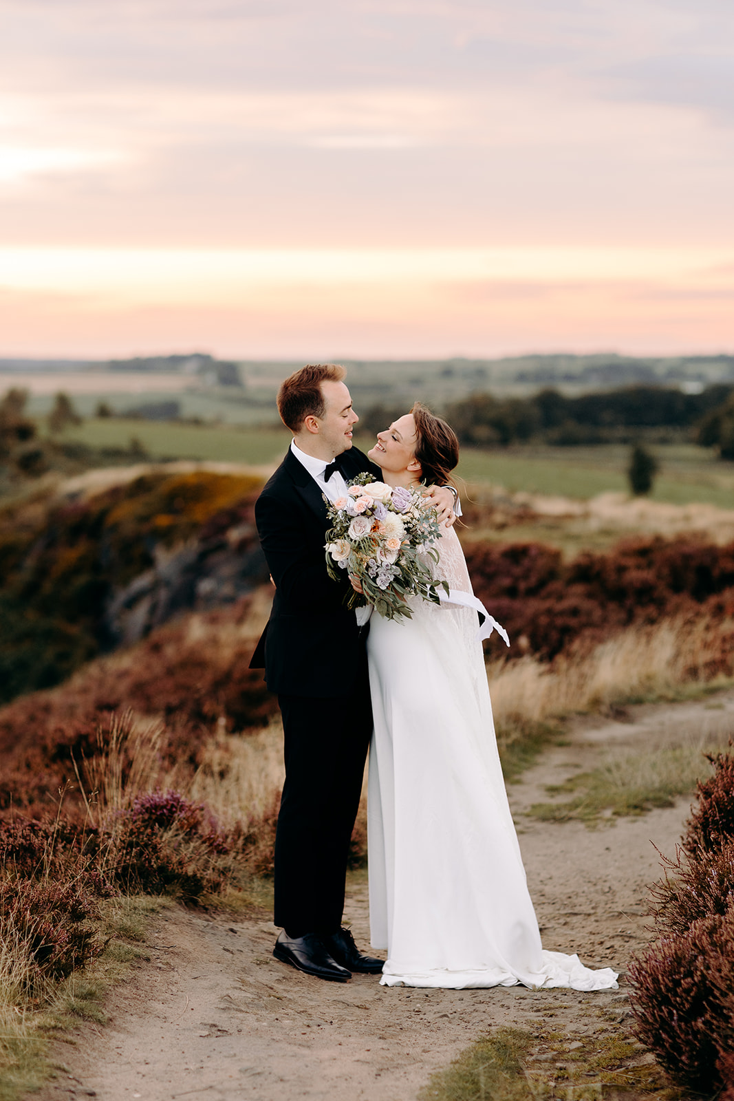 Candid moment of the couple embracing against the orange sky – dreamy Darwin Lakes wedding portrait.