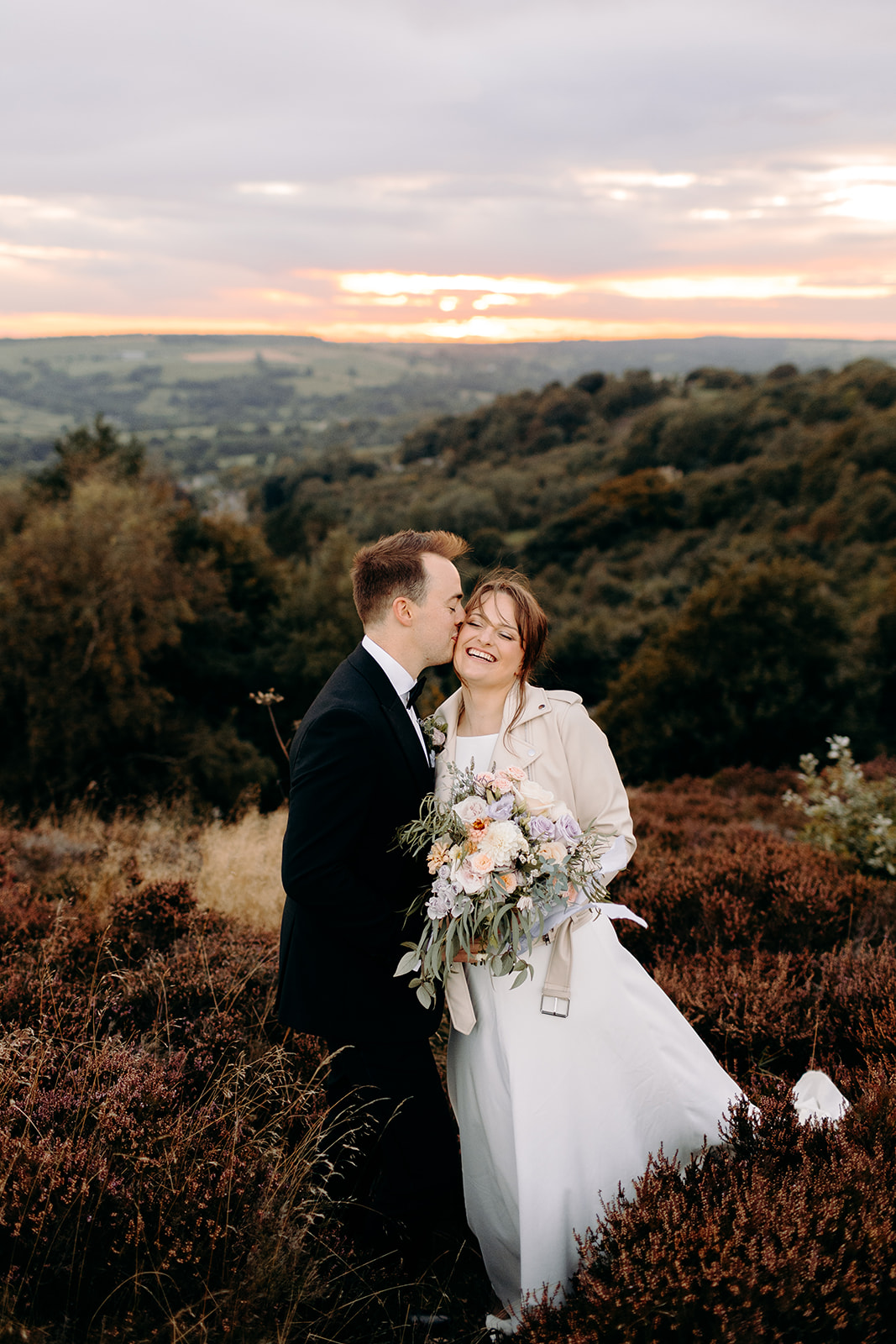 The bride leans into the groom’s shoulder with her bouquet in view – soft and natural Peak District wedding moment.