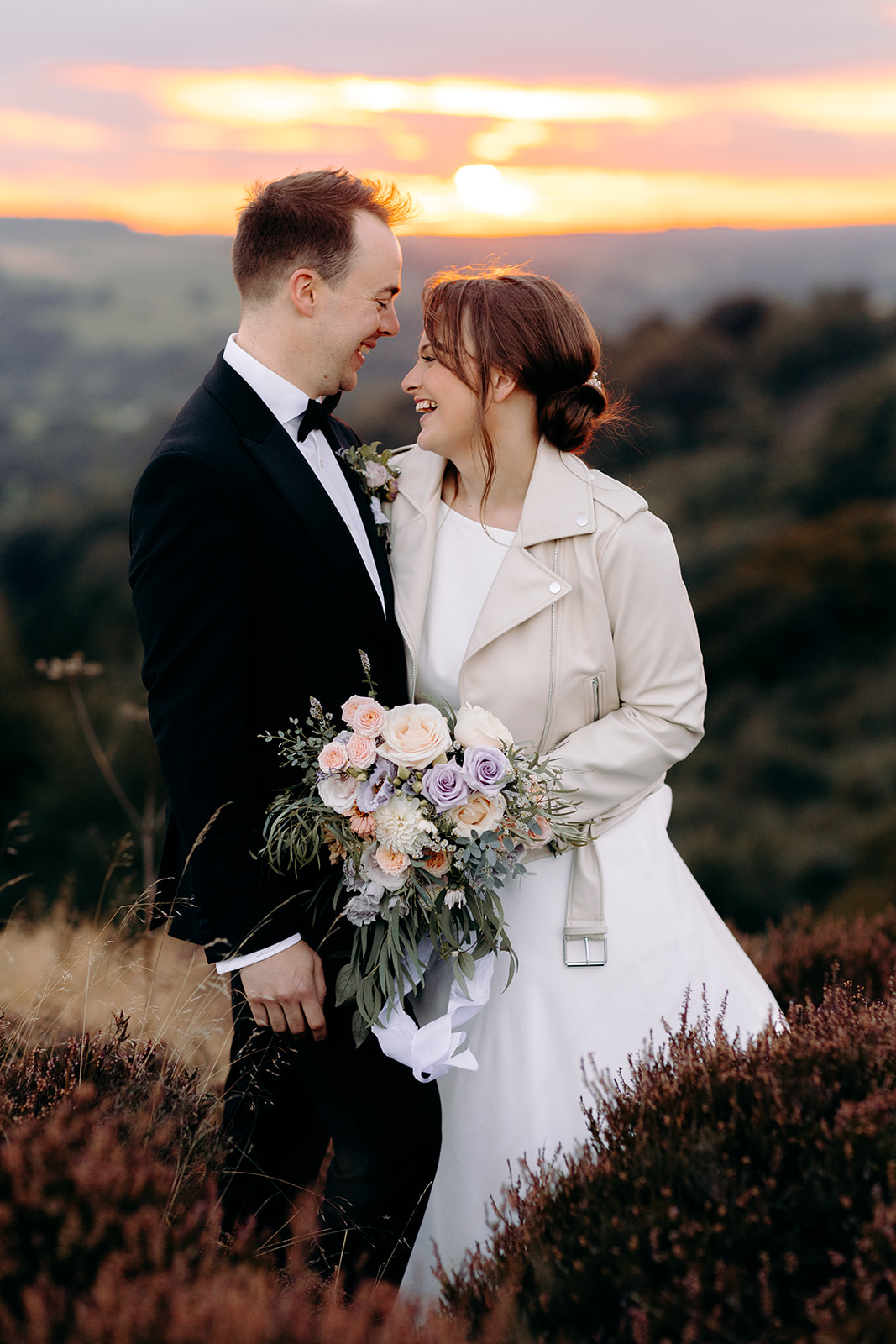 Couple smiling at each other as sun dips behind them – warm and romantic wedding photography.
