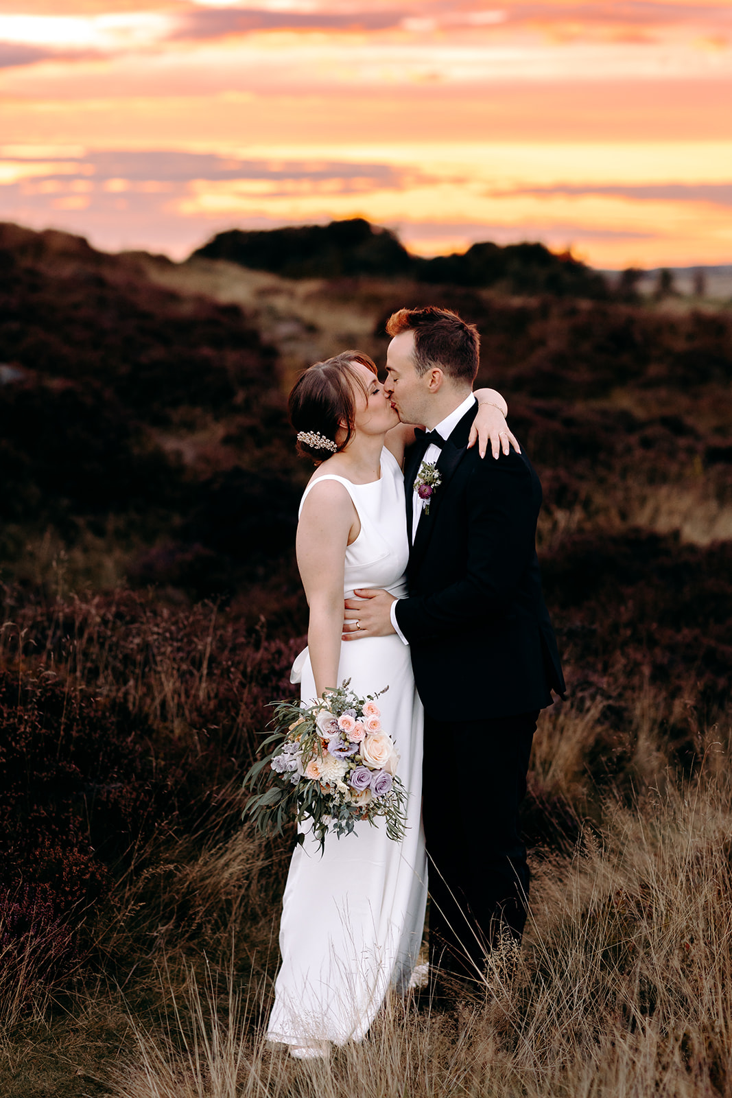 Groom wraps arms around bride as golden light hits the horizon – dreamy Peak District wedding moment.