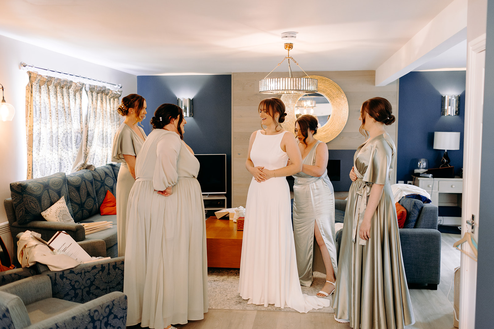 Bridesmaids helping the bride into her elegant wedding dress – relaxed wedding photography with real emotion.