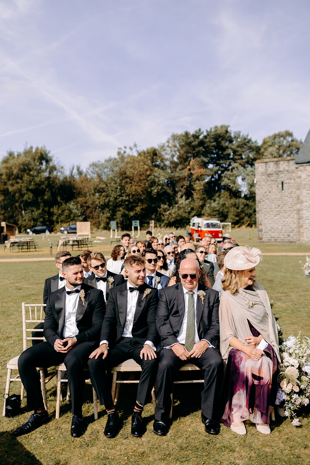 Wide shot of the ceremony setup with guests seated outdoors – rustic wedding editorial scene.