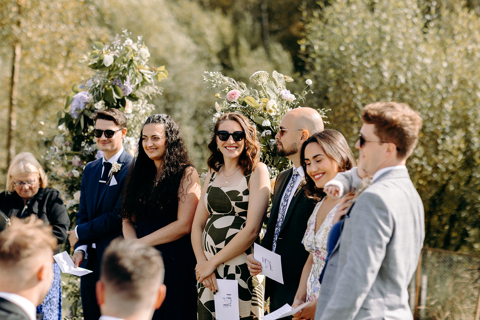 Friends of the bride and groom doing a reading during the lakeside wedding ceremony.