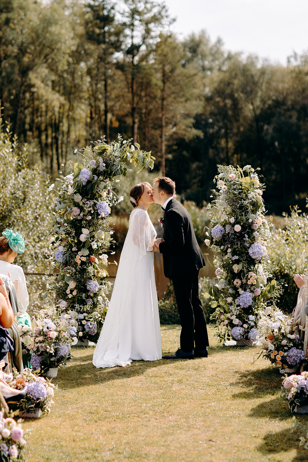 Natural photo of the bride and groom sharing their first kiss, with wild flowers and Darwin Lake behind them - natural, candid wedding photography in the Peak District.