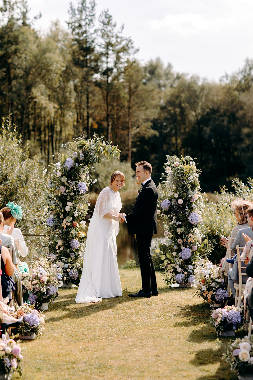 Natural photo of the bride and groom laughing together after their first kiss, with wild flowers and Darwin Lake behind them - natural, candid wedding photography in the Peak District.