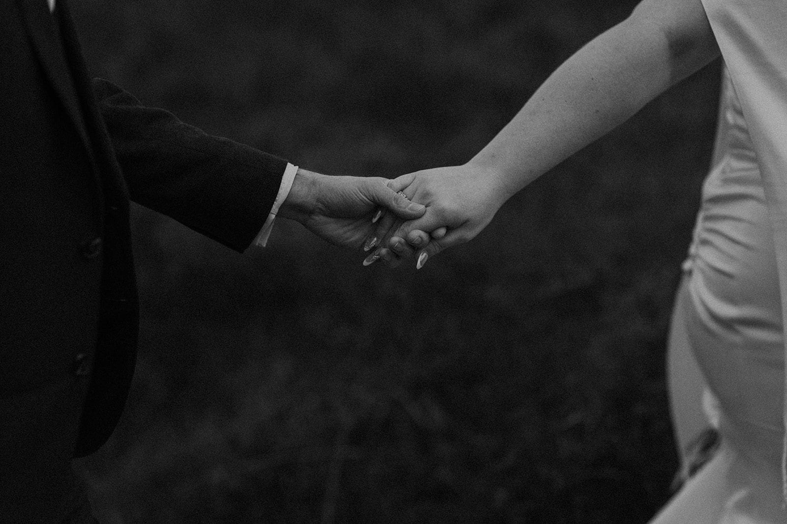 Detailed black and white photo of bride and groom holding hands and running through the Scottish Highlands