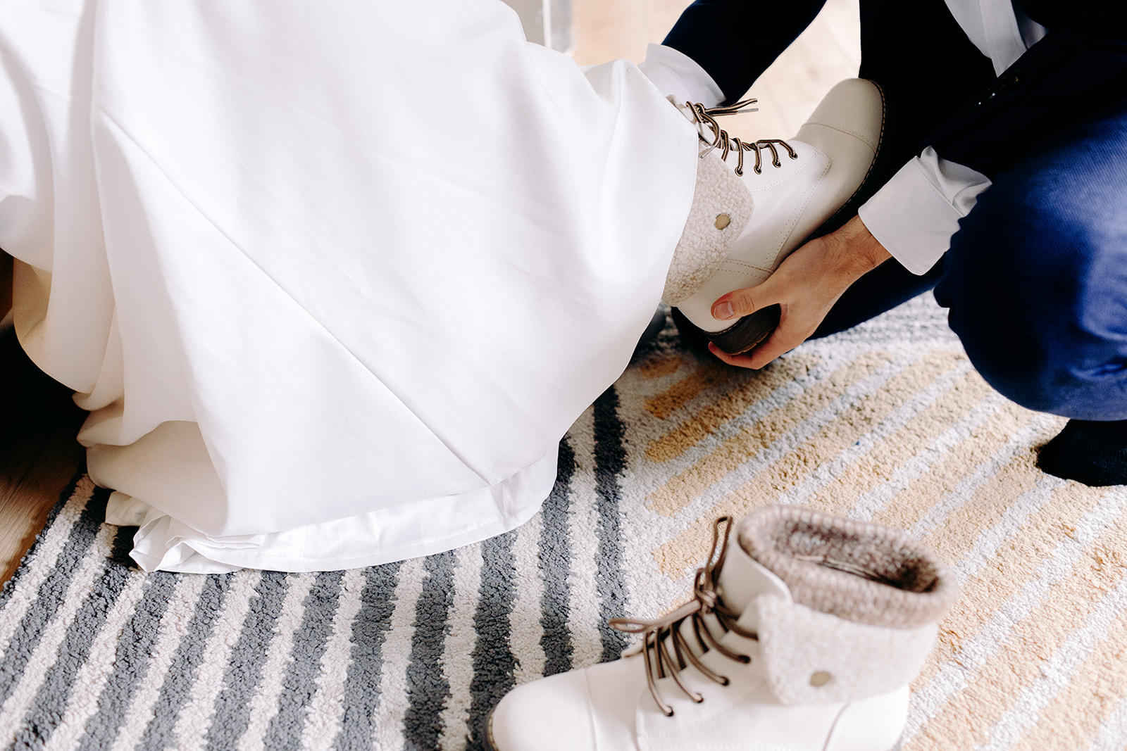 Bride stepping into boots with help from groom, a unique twist on a Skye elopement morning.