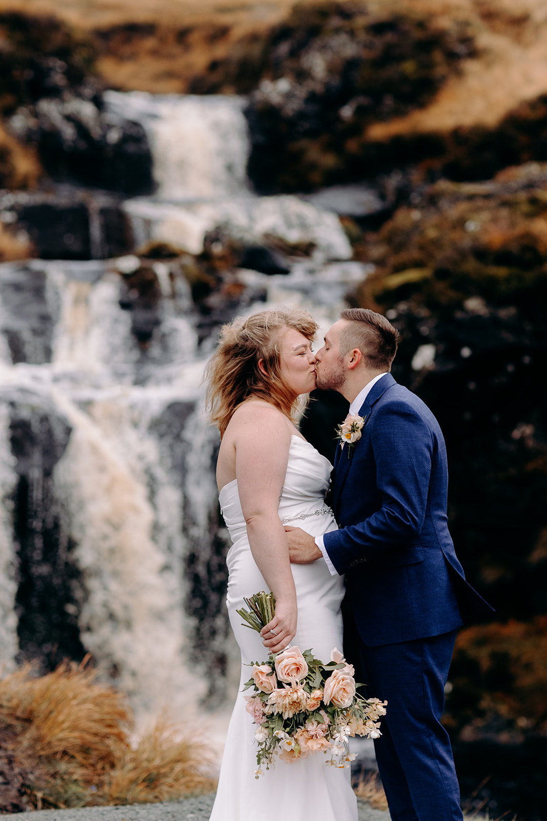 Couple kissing beside a dramatic waterfall in Isle of Skye elopement