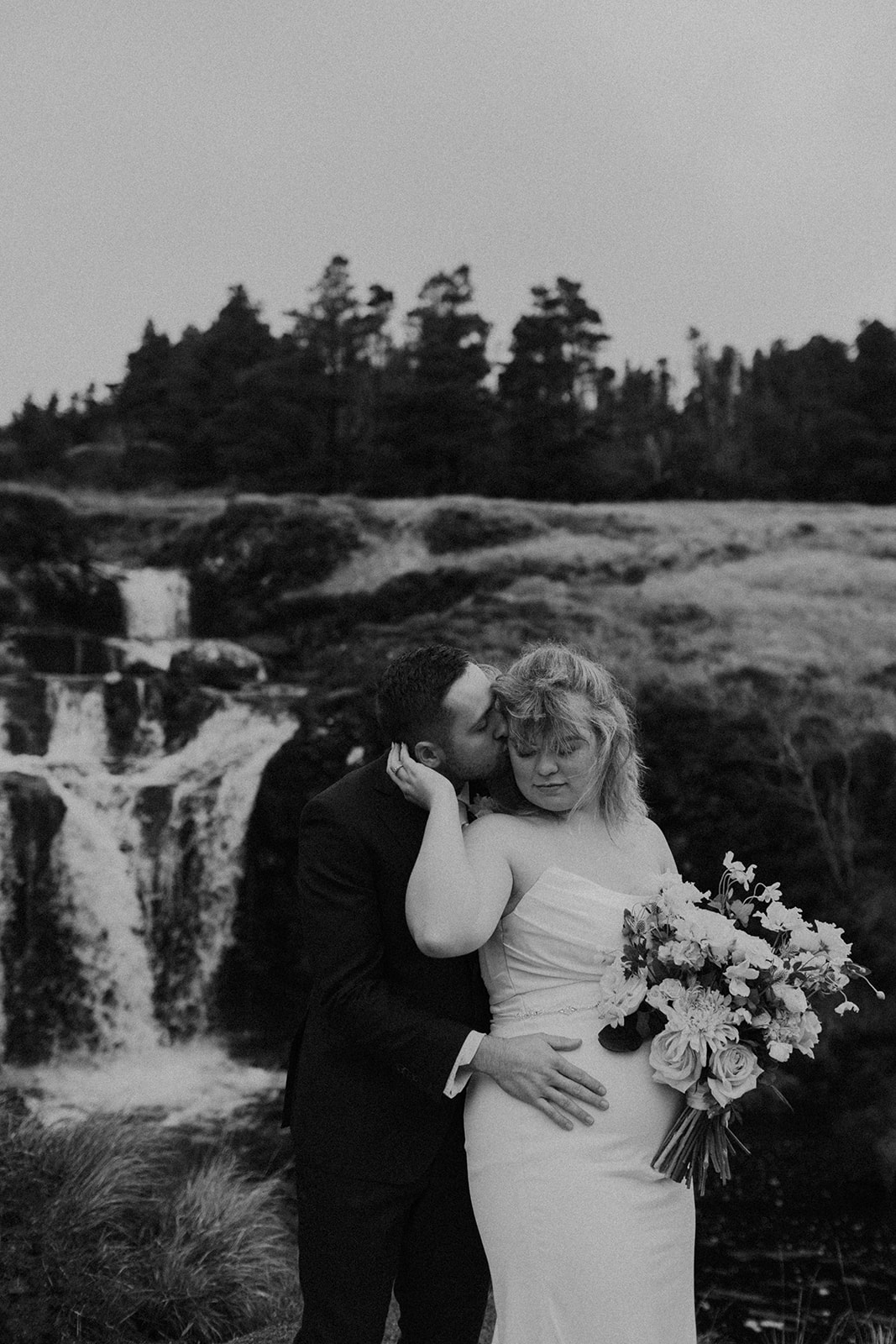 Black and white romantic kiss at Skye waterfall during elopement