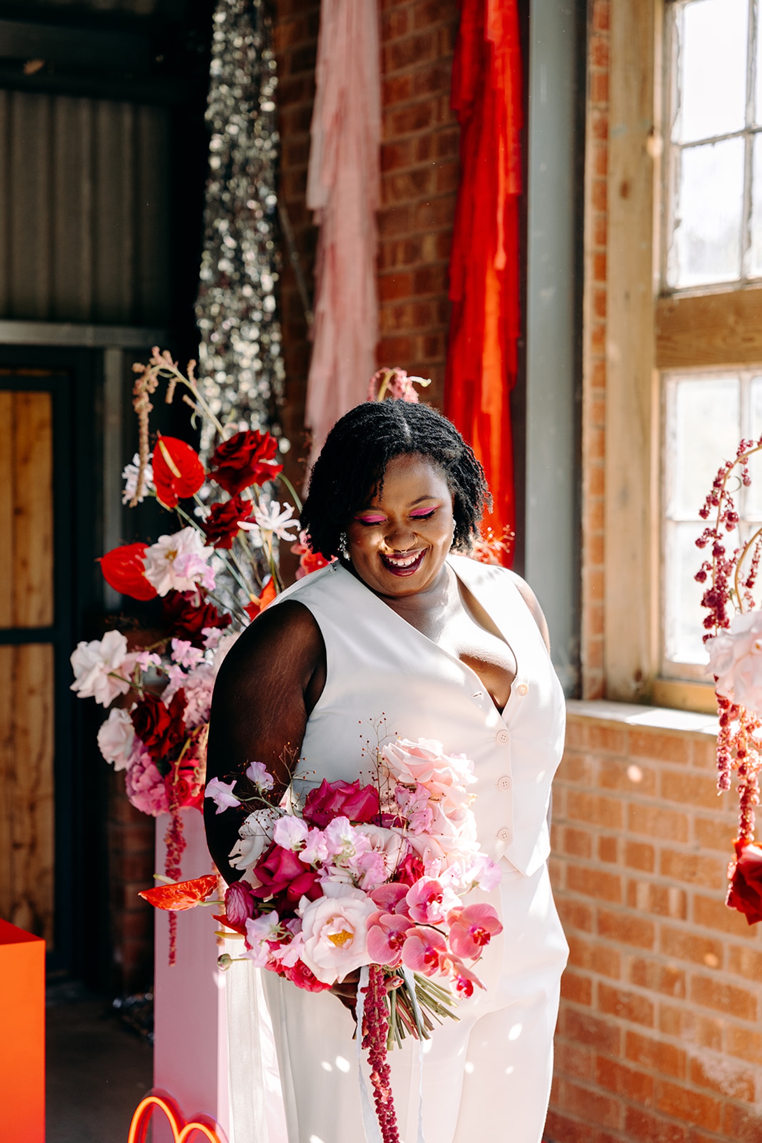 Bride admiring her bright pink wedding bouquet at The Giraffe Shed, North Wales