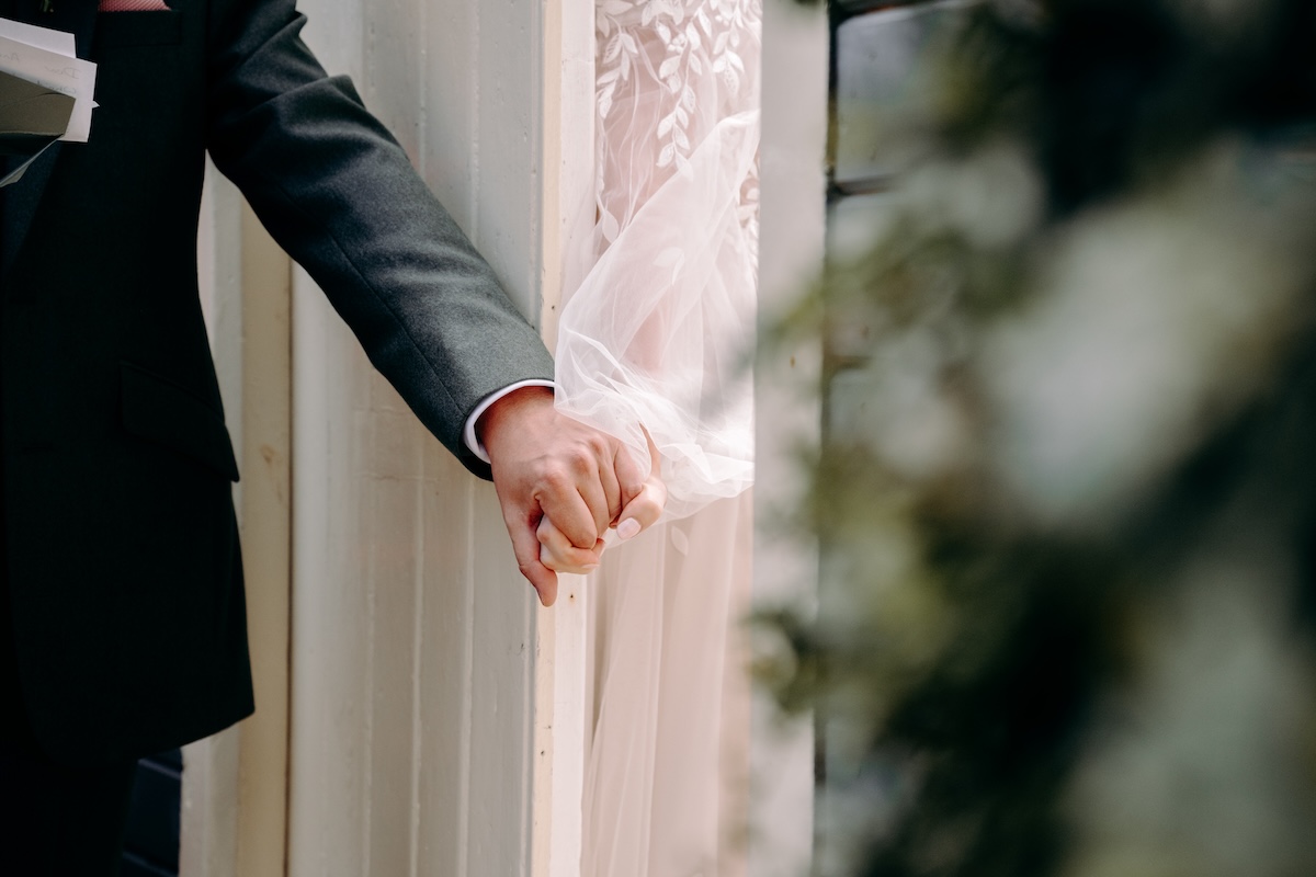 Close-up of the couple’s hands intertwined during their letter exchange – romantic touch at a fun Marleybrook House wedding.
