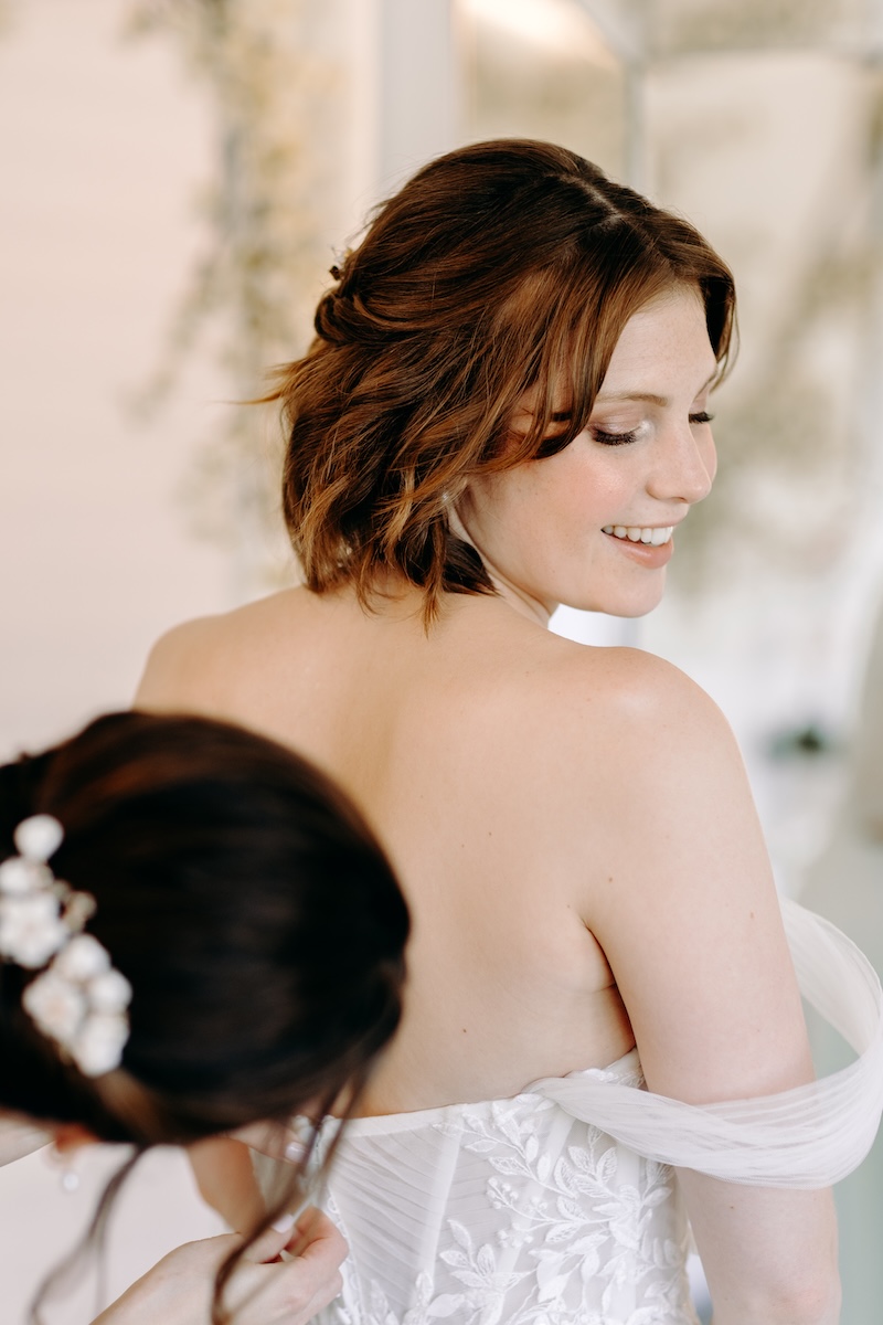 Bridesmaid helping with the bride’s corset lacing – detailed prep moment at a Marleybrook House wedding.