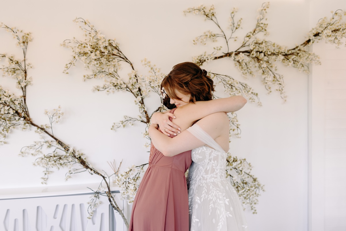 Bride and bridesmaid sharing a joyful hug before the ceremony – emotional moment at Marleybrook House wedding.