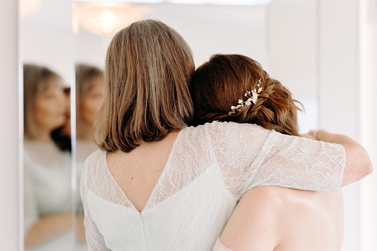 Bride warmly embracing her mum indoors with eyes closed – meaningful connections captured at Marleybrook House.