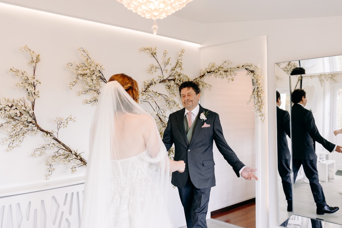 Bride having a first look with her dad inside the bridal suite – natural and emotional wedding photography in Kent.