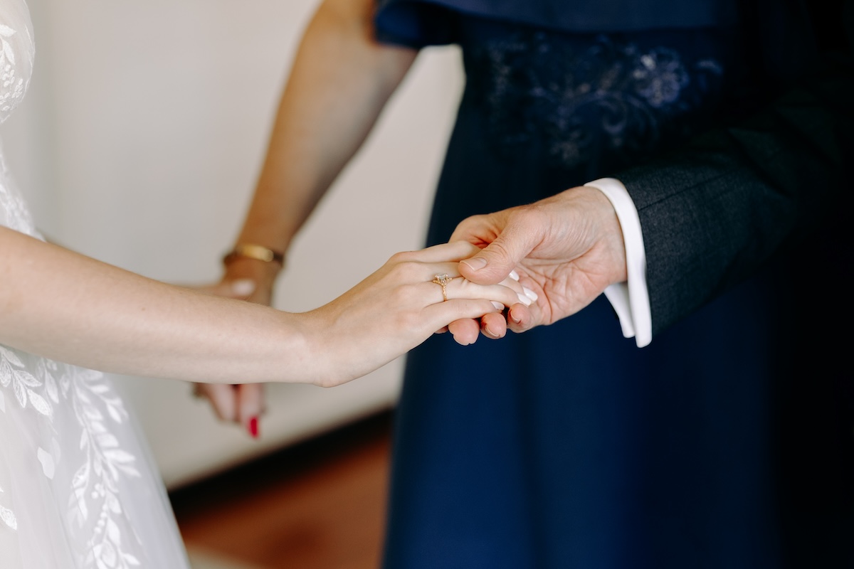 Close up of hands being held whilst the bride has an intimate moment with her dad & step-mum inside the bridal suite – natural and emotional wedding photography in Kent.