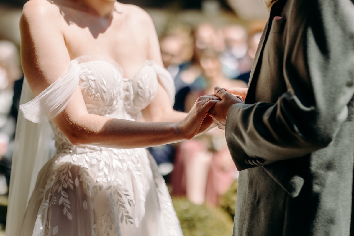 Close-up of the bride holding her handwritten vows, her off-shoulder gown catching the light – natural wedding photography at Marleybrook House.