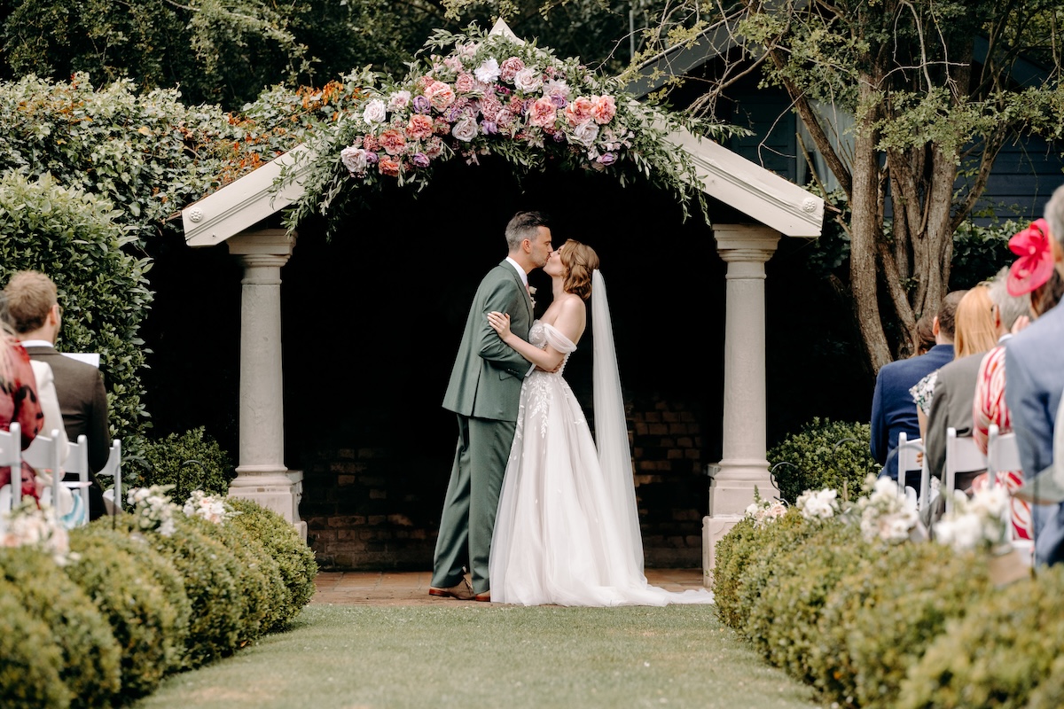 Bride and groom sharing their first kiss as a married couple – meaningful moment in natural wedding photography style.