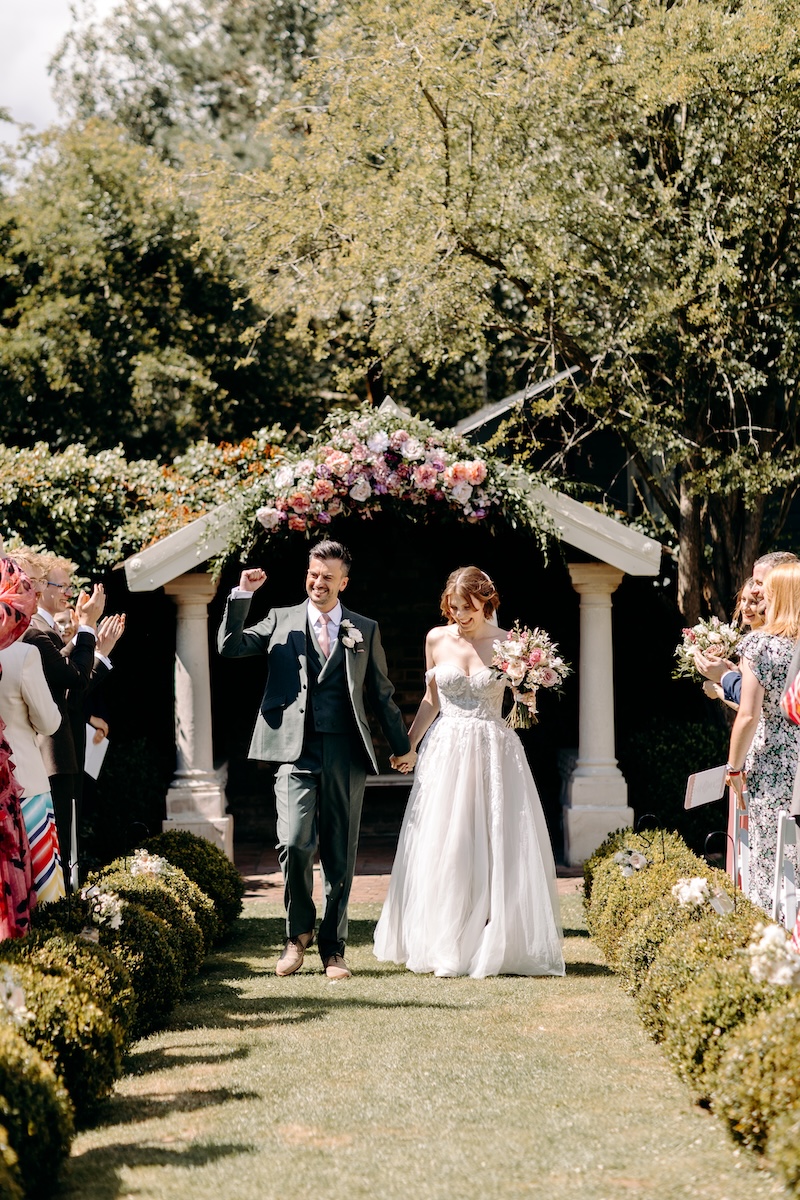 Newlyweds beam at each other as they make their way down the aisle, guests celebrating around them – joyful Marleybrook House wedding moment.