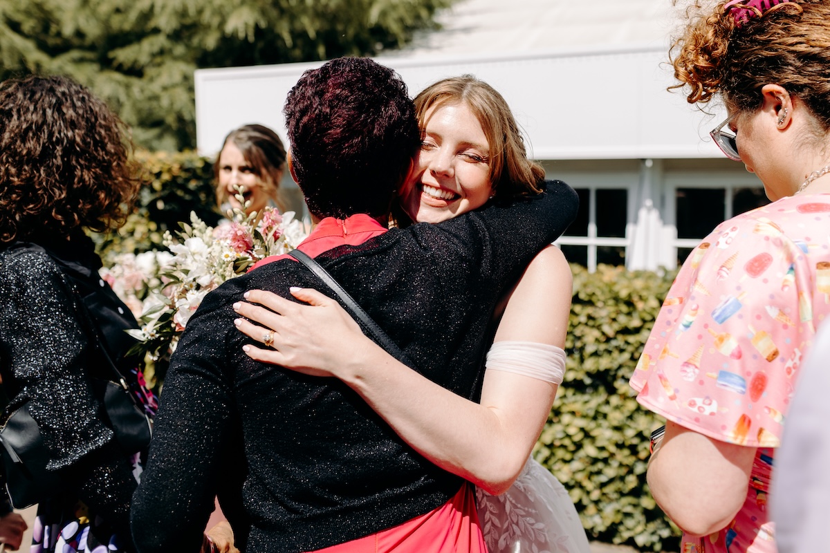 Natural moment of the bride hugging a guest, with real emotion and warmth.