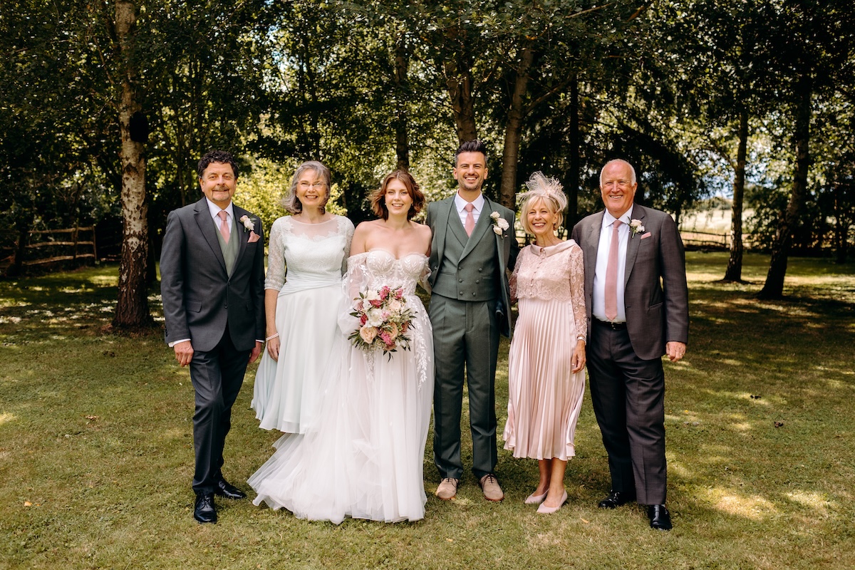Relaxed family portrait under the trees, captured with a natural wedding photography approach.