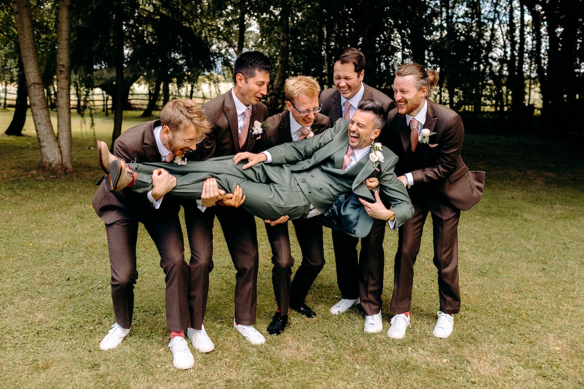 Playful groomsmen jumping photo on the lawn – fun, relaxed wedding photography at Marleybrook House.