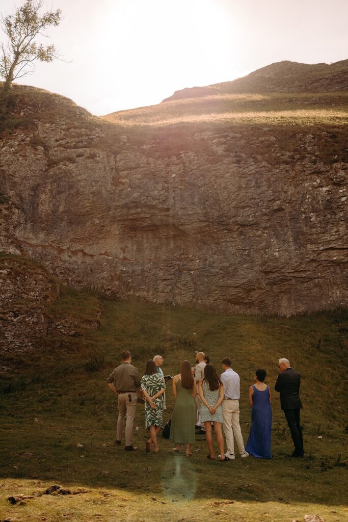 Ceremony group standing in a sheltered limestone nook during the couple’s Peak District elopement.