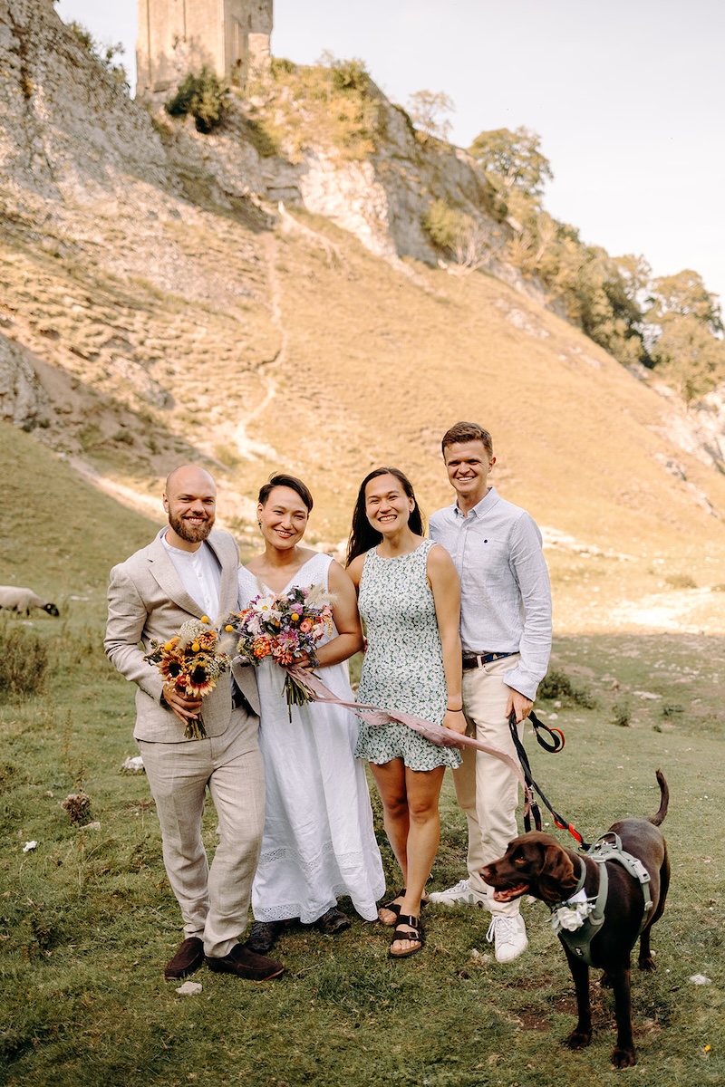 Couple celebrating their Peak District elopement with close family and their dog in a rocky valley.