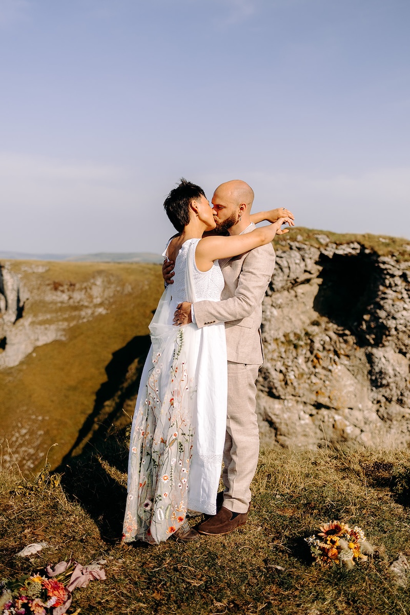 Couple kissing on a rocky Peak District outcrop during their outdoor elopement ceremony.