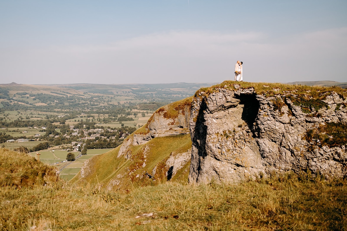 Warm sunset embrace on a hillside captured by a Peak District elopement photographer.