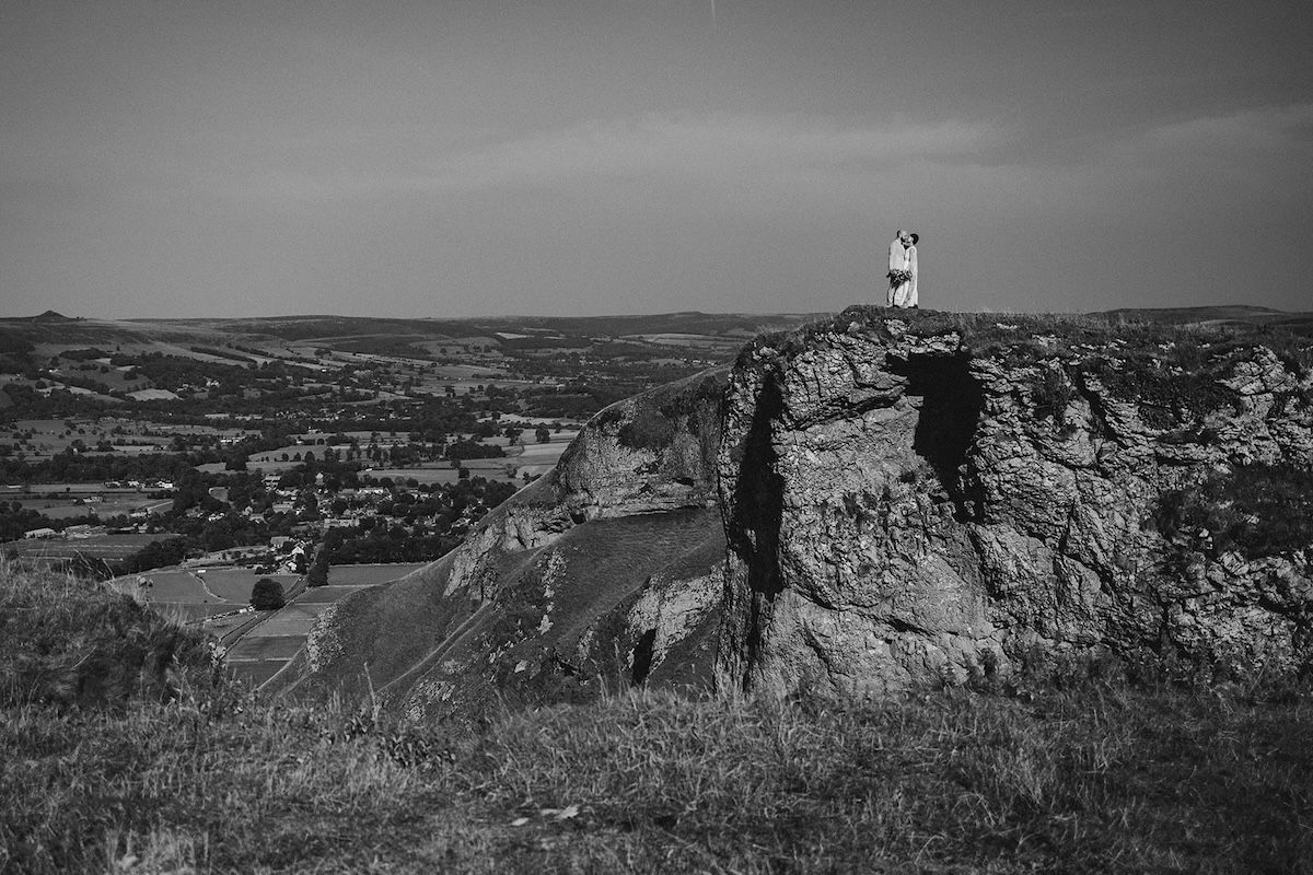 Black and white couple’s portrait on cliffs photographed by a Peak District elopement photographer.
