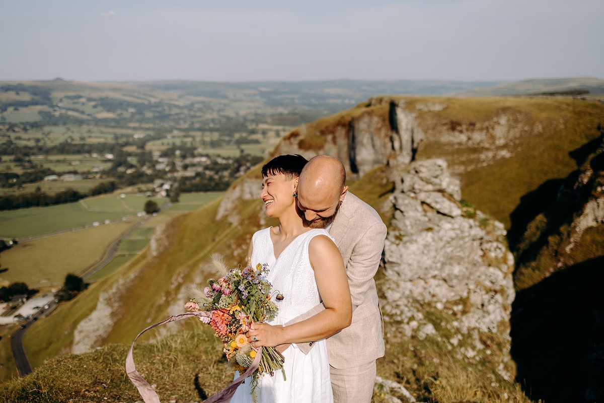 Couple standing on tall rock formations during their ceremony, captured by a Peak District elopement photographer.