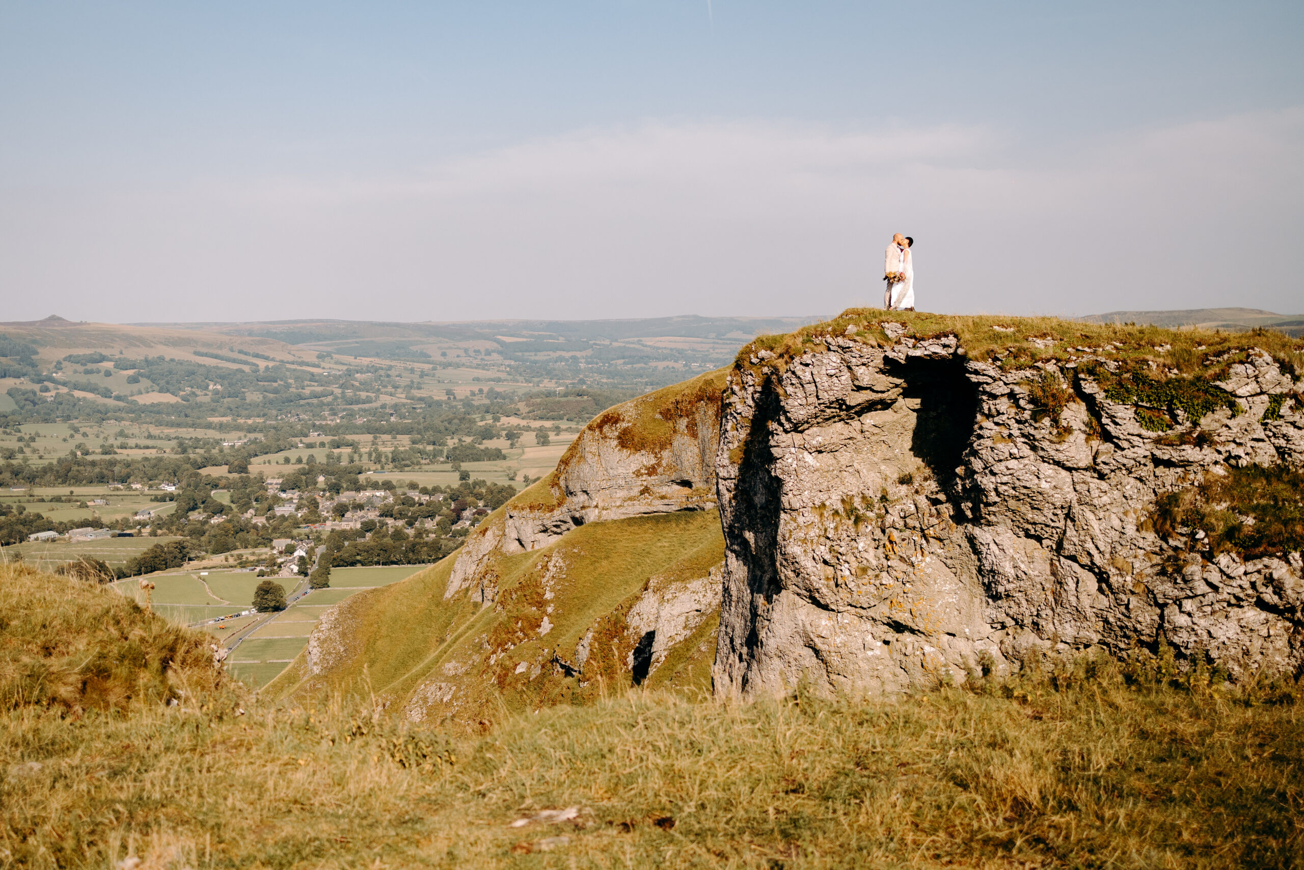 Warm sunset embrace on a hillside captured by a Peak District elopement photographer.