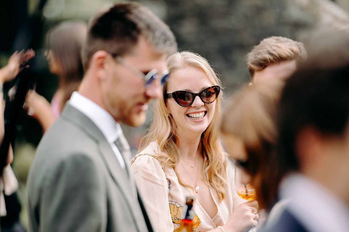 Guests mingling outside marquee during wedding reception at Eyam Hall in Derbyshire.