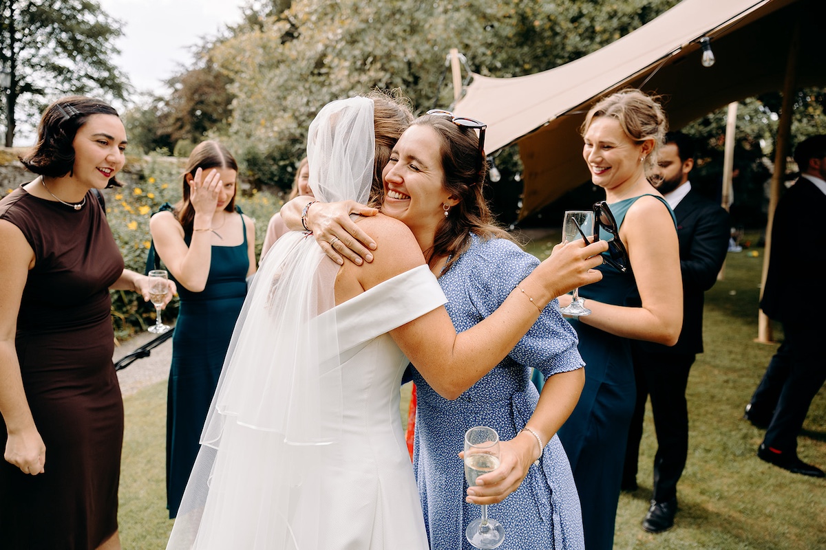 Candid photo of hugs and greetings during drinks reception at Eyam Hall marquee wedding.