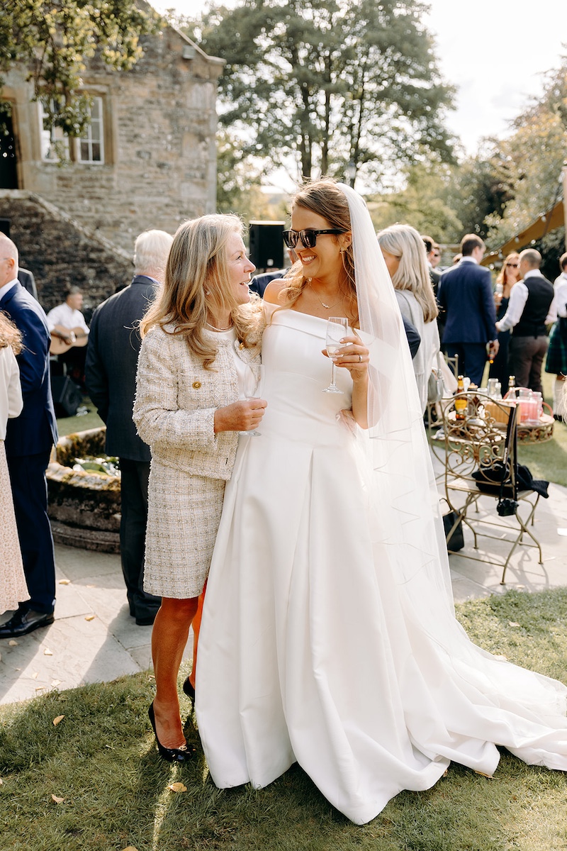 Bride and mother of the bride posing for natural photo during Eyam Hall wedding reception.