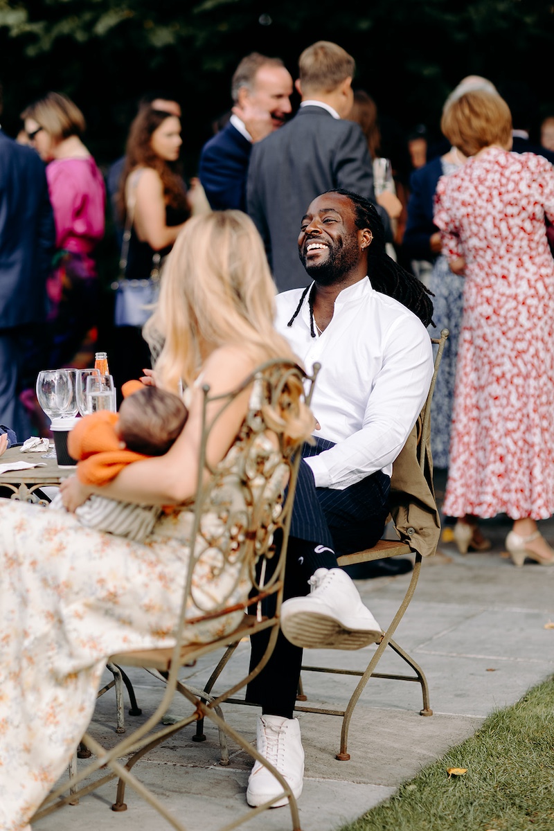 Wedding guests chatting and laughing outside marquee during Eyam Hall reception drinks.
