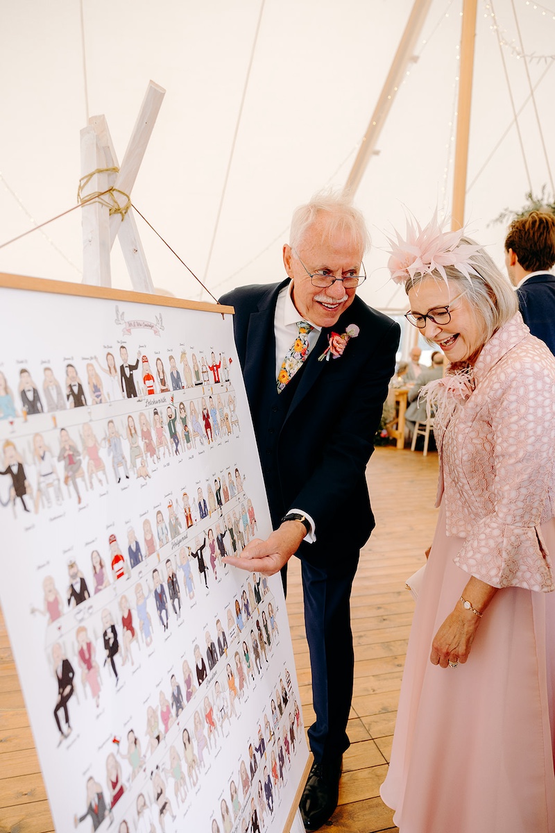Guests browsing wedding seating plan display and laughing together – Derbyshire wedding photographer candid style.