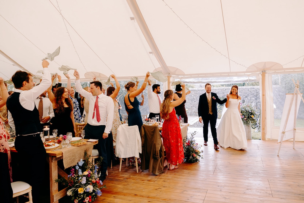 Guests raising glasses and toasting during marquee wedding speeches at Eyam Hall.