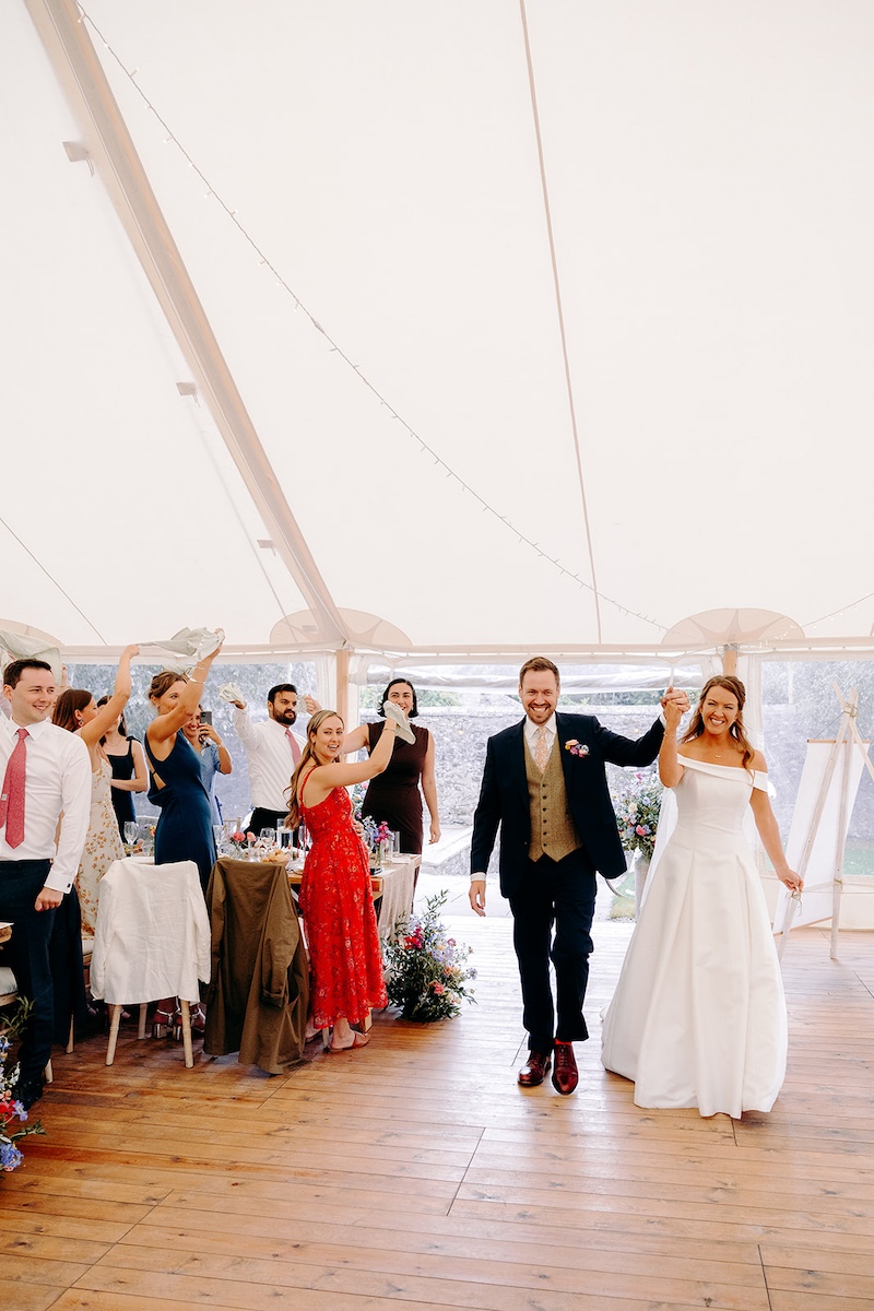 Guests raising glasses and toasting during marquee wedding speeches at Eyam Hall.